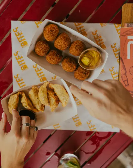 bitterballen en gyoza met een sausje pakken handen