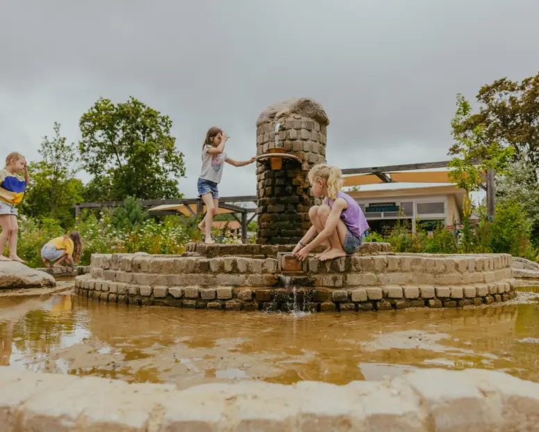 kinderen meisjes spelen in de fontein op het ontmoetingsplein